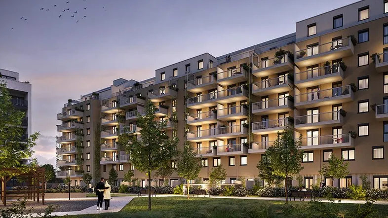 Moderne Wohnanlage mit mehreren Balkonen und begrünten Außenbereichen bei Sonnenuntergang.
