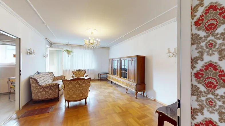 Geräumiges Wohnzimmer mit klassischem Parkettboden, eleganten Möbeln und Kronleuchter, bereit zur Renovierung.