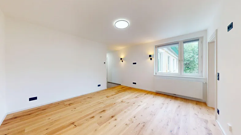 Helles Zimmer mit neuem Holzboden und großen Fenstern, ideal als Wohnbereich nutzbar.