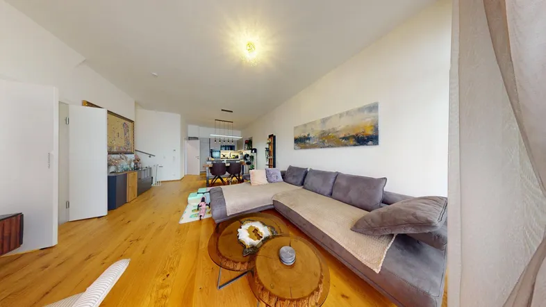 Geräumiges Wohnzimmer mit großem Ecksofa, Holzboden und offener Verbindung zur Küche.