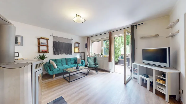 Helles Wohnzimmer mit gemütlichem Sofa, Fernseher und direktem Zugang zur Terrasse.