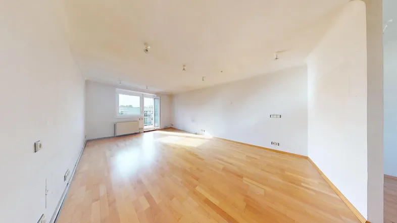Helles, leeres Wohnzimmer mit Parkettboden und Zugang zu einem Balkon, bereit zur individuellen Gestaltung.