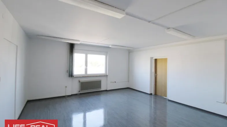 Geräumiger, leerer Büroraum mit großen Fenstern, hellen Wänden und glänzendem Bodenbelag.