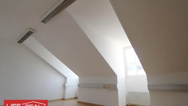 Heller Dachgeschossraum mit schrägen Wänden, Laminatboden und einem Fenster, das Tageslicht hereinlässt.