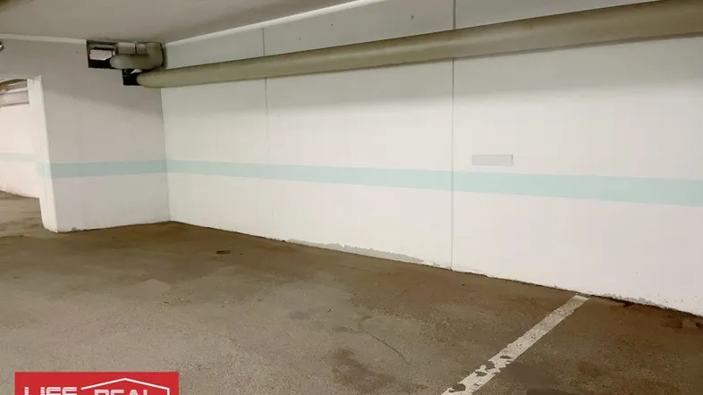 Tiefgaragenstellplatz mit weiß gestrichenen Wänden und Betonboden in einem gepflegten Zustand.