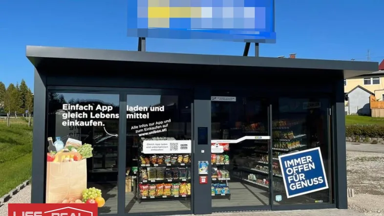Modernes, freistehendes Ladenlokal mit großen Glasfronten und einem Werbeschild auf dem Dach.