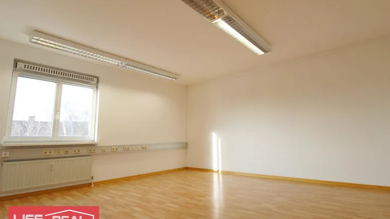 Heller Raum mit Holzfußboden, großem Fenster und Deckenbeleuchtung, ideal als Büro oder Arbeitszimmer.