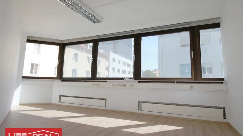 Helles Büro mit großen Fenstern und hellem Laminatboden, ideal für produktives Arbeiten.