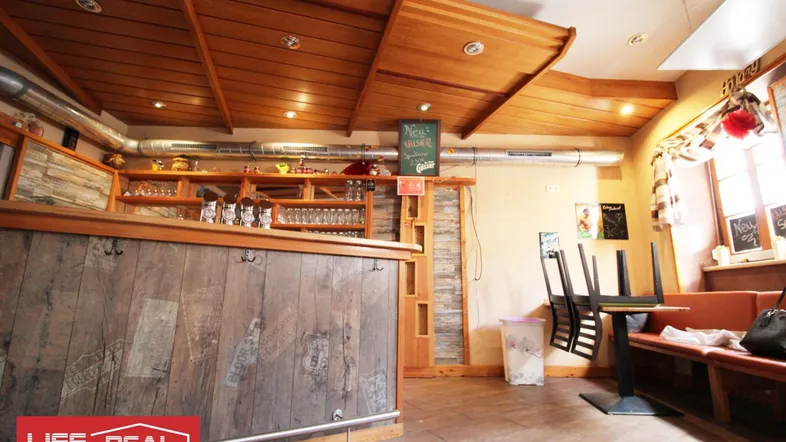 Rustikaler Barbereich mit Holzverkleidung, Holzbalkendecke und Fliesenboden in einem Gewerbeobjekt.