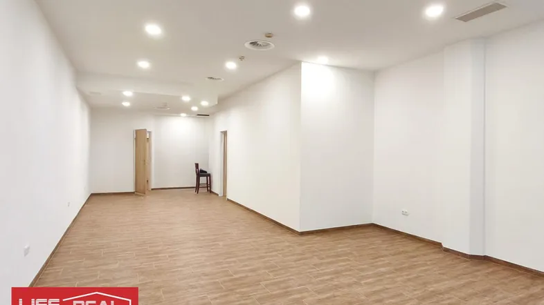 Leerer, heller Gewerberaum mit Fliesenboden und Einbaustrahlern an der Decke, bereit zur Nutzung.