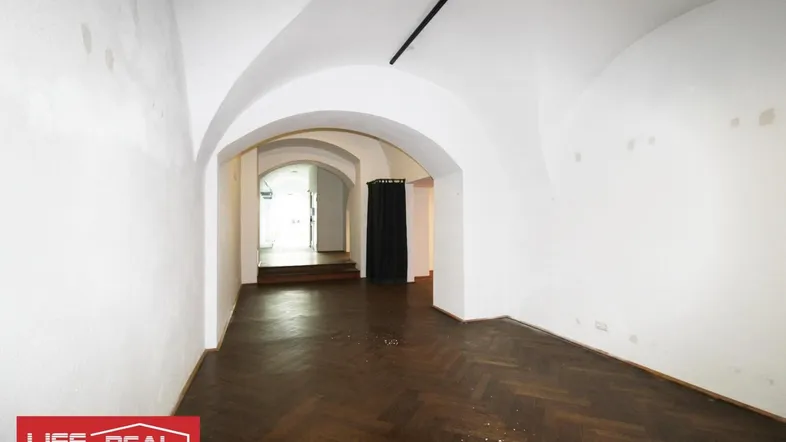 Geräumiger Innenraum mit markanten Gewölbedecken, dunklem Fischgrätparkett und weiß gestrichenen Wänden.