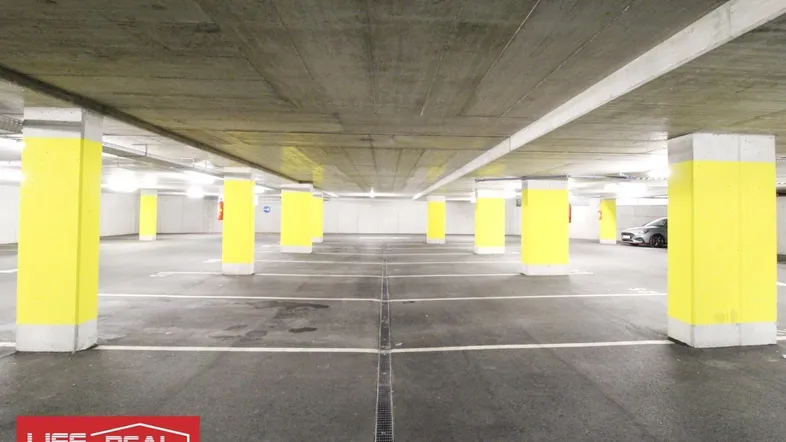 Tiefgarage mit leuchtend gelben Säulen und markierten Parkplätzen, gut beleuchtet und geräumig.