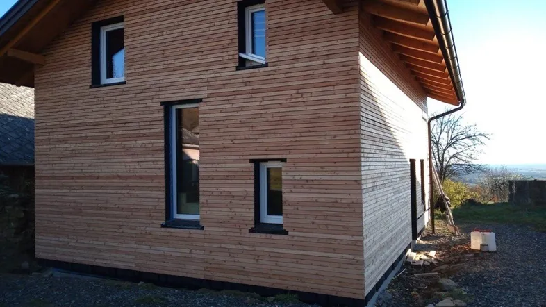 Neubau eines Einfamilienhauses mit Holzfassade und Satteldach in ländlicher Umgebung.