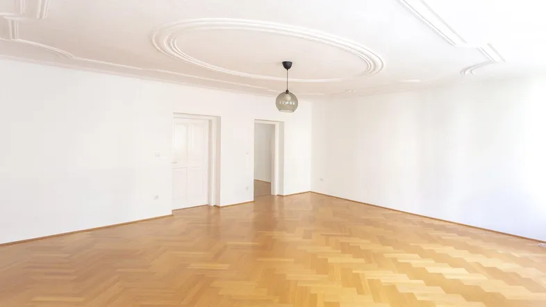 Helles, leeres Zimmer mit Fischgrätparkett und Stuckdecke, bereit zur individuellen Gestaltung.
