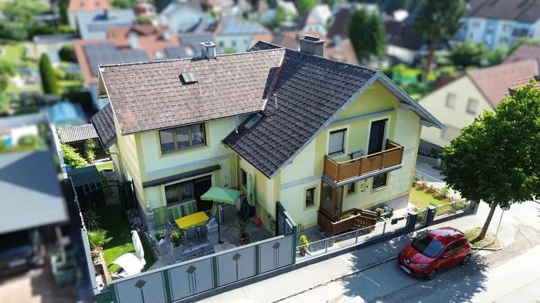 Drohnenaufnahme eines Einfamilienhauses mit Garten, Terrasse und Balkon in einer Wohnsiedlung.