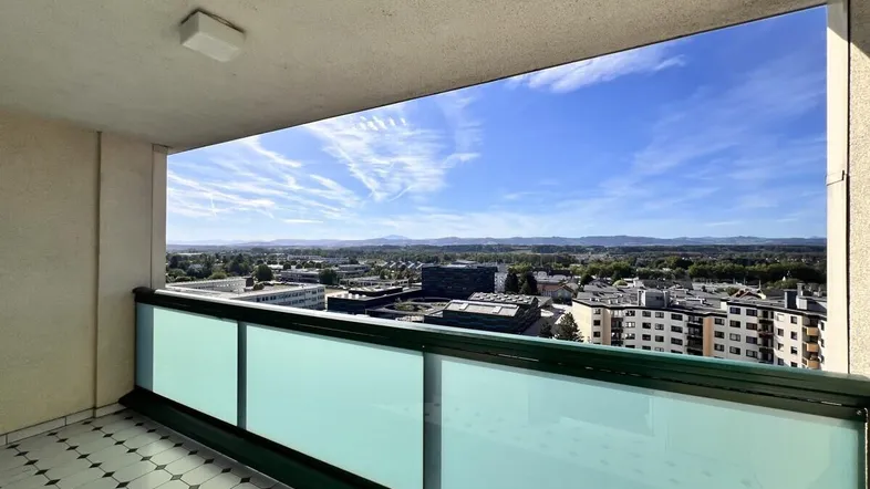 Geräumiger Balkon mit Fliesenboden und weitem Blick über die Stadt und die umliegende Landschaft.