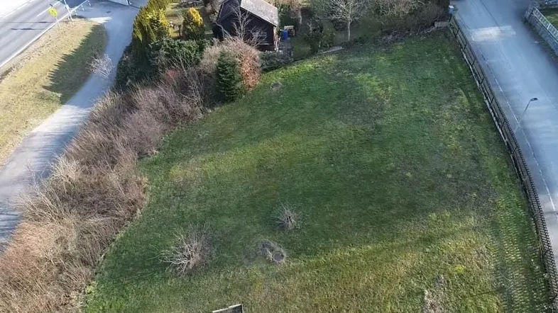 Luftaufnahme eines unbebauten Grundstücks mit Rasenfläche, umgeben von Straßen und Häusern.