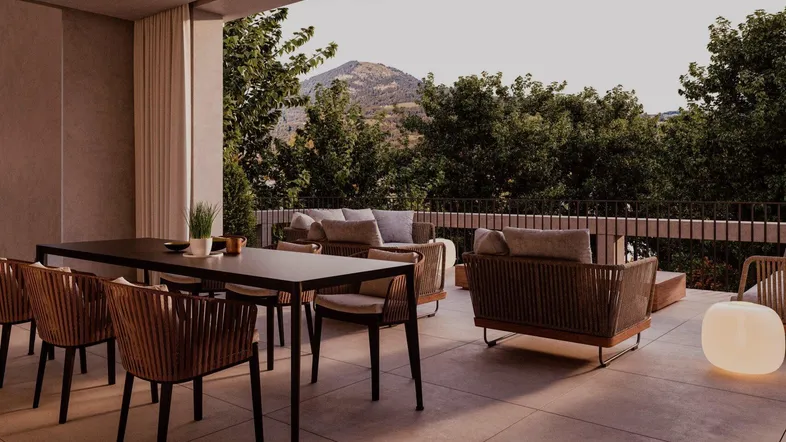 Geräumige Terrasse mit Essbereich und Lounge-Möbeln, umgeben von grüner Natur und Bergblick.