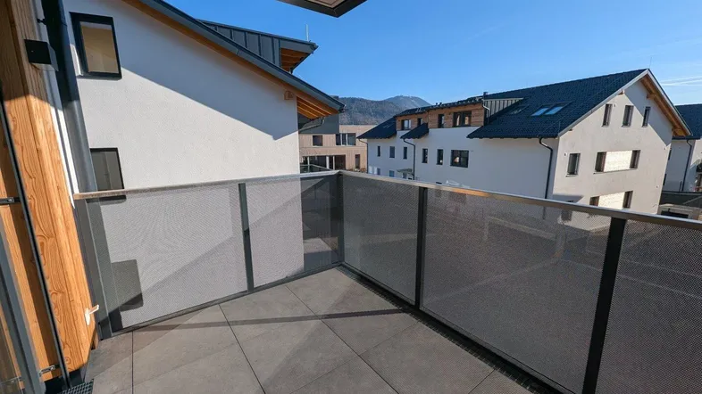 Heller Balkon mit Fliesenboden und Blick auf die umliegenden Gebäude und Berge.