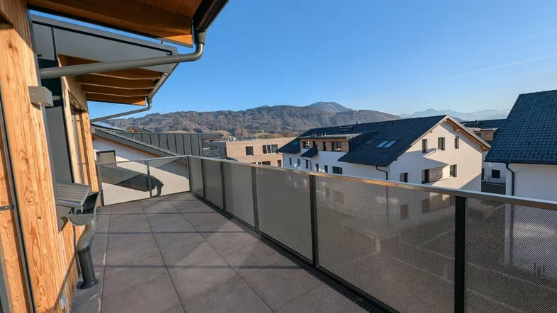 Geräumiger Balkon mit Fliesenboden und modernem Geländer, bietet einen weiten Blick auf die Berge.