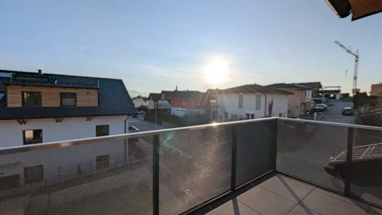 Sonnige Terrasse mit Fliesenboden und Blick auf die umliegende Wohngegend bei Sonnenuntergang.