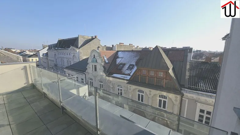 Geräumige Dachterrasse mit Glasgeländer und weitem Blick über die Dächer der Stadt.