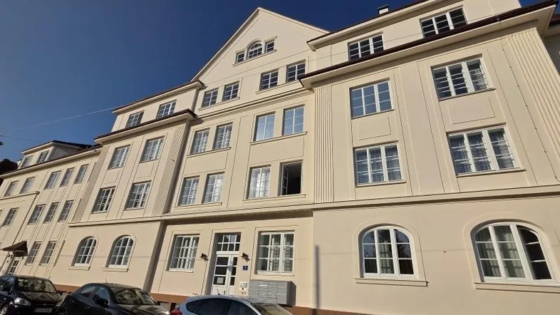 Ansicht der hellen Fassade eines Mehrfamilienhauses mit vielen Fenstern und klassischer Architektur.