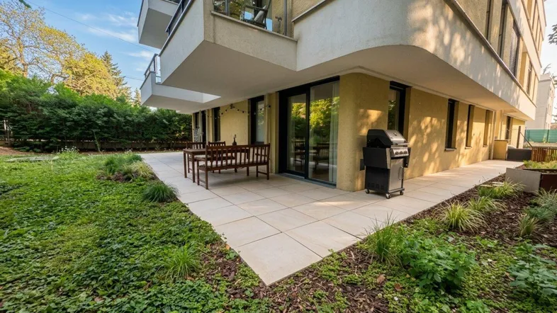 Eine einladende Terrasse mit Gartenmöbeln und Grill, umgeben von Grünflächen und moderner Architektur.