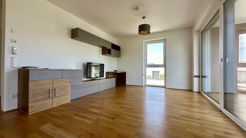 Helles Wohnzimmer mit Parkettboden, großen Schiebetüren zum Balkon und moderner Einrichtung.