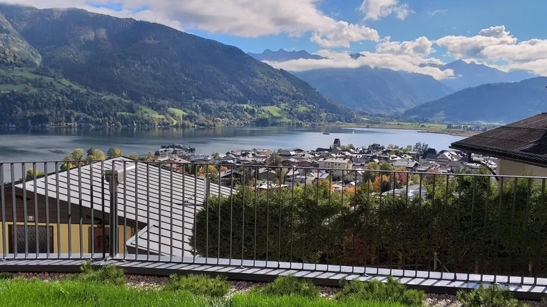 Panoramablick auf einen malerischen See, eine charmante Stadt und majestätische Berge von einem erhöhten Aussichtspunkt.