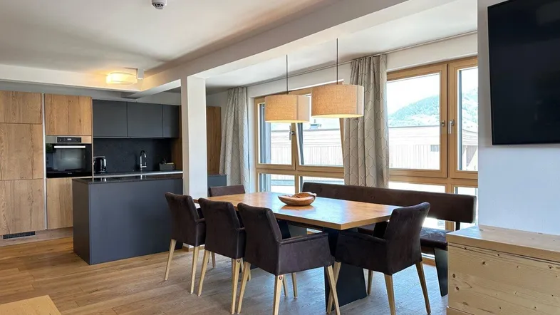 Moderne offene Küche mit Essbereich, Holzboden und großen Fenstern mit Bergblick.