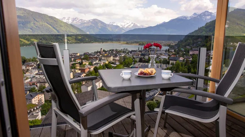 Balkon mit Sitzgelegenheiten und atemberaubendem Blick auf den See und die umliegenden Berge.