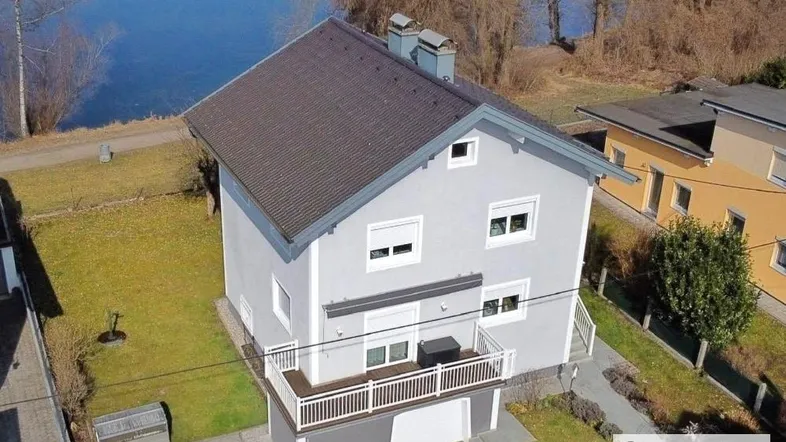 Luftaufnahme des Hauses am See mit umliegender Grünfläche und Zufahrt.