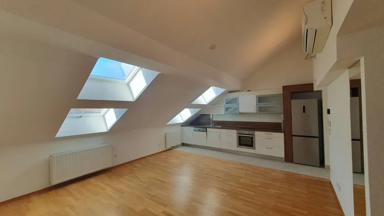 Helle Dachgeschosswohnung mit moderner Einbauküche, Holzboden und mehreren Dachfenstern für viel Tageslicht.