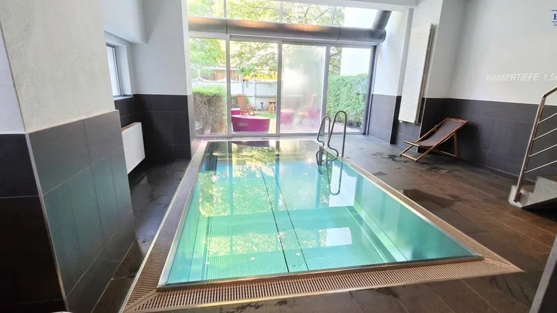 Modernes Hallenbad mit großen Glasfronten und Blick ins Grüne, ideal zur Entspannung.