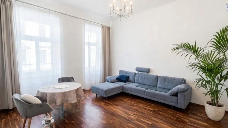 Helles Wohnzimmer mit Holzboden, bequemer Couch und einem kleinen Esstischbereich.