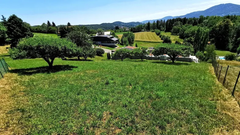 Weitläufiges Grundstück mit grüner Wiese, Bäumen und Fernblick auf die umliegende Landschaft und Berge.