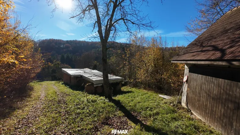Kleines Gebäude in ländlicher Umgebung mit herbstlicher Vegetation und sonnigem Himmel.