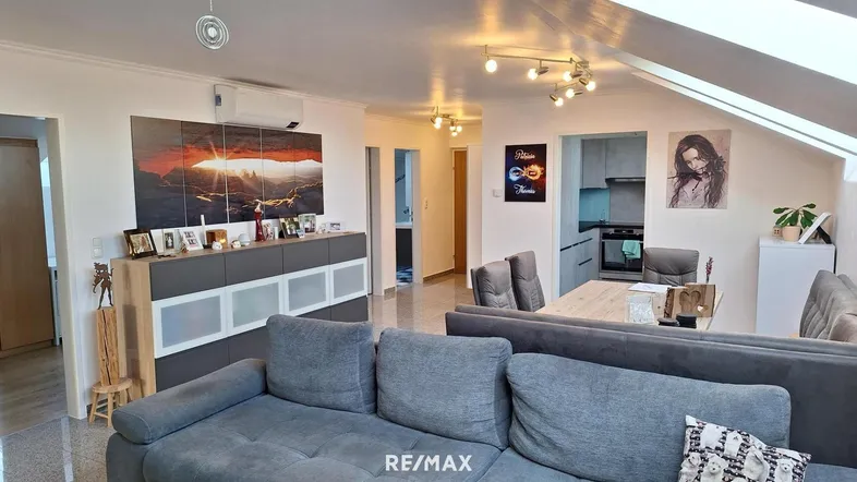 Geräumiger Wohn-Essbereich mit gemütlichem Sofa, Essbereich und offener Küche im Dachgeschoss.