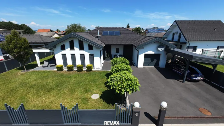 Luftaufnahme eines modernen Einfamilienhauses mit Carport und gepflegtem Vorgarten.