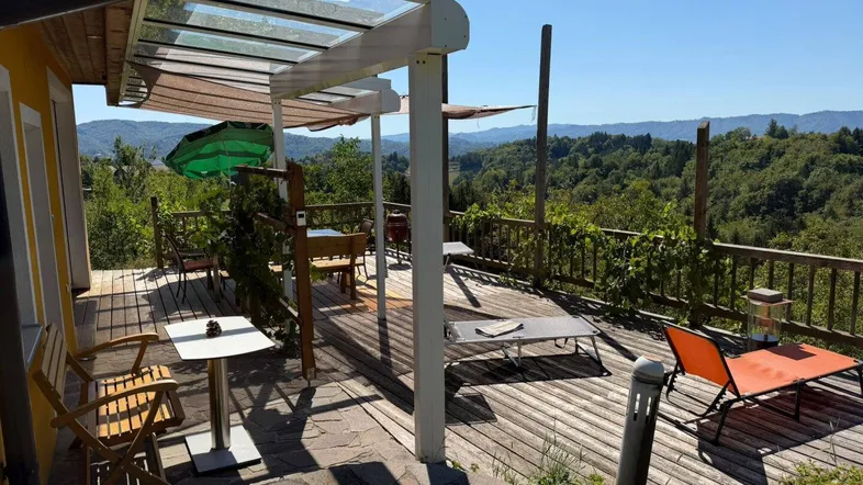 Große Holzterrasse mit Sitzgelegenheiten und Überdachung, bietet einen weiten Blick ins Grüne.
