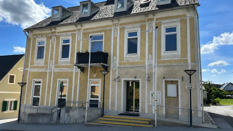 Historisches Gebäude mit verzierter Fassade, kleinem Balkon und barrierefreiem Zugang über eine Rampe.