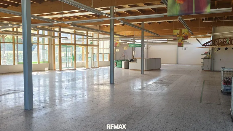 Großer, leerstehender Verkaufsraum mit Fliesenboden und vielen Fenstern, bereit für neue Nutzung.