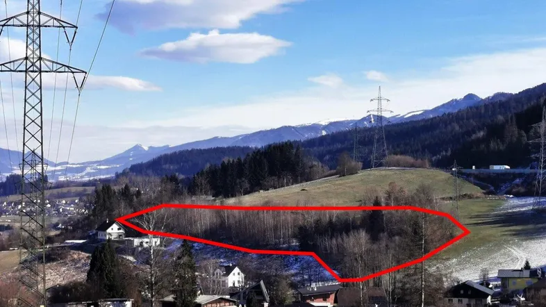 Luftaufnahme des Grundstücks mit umliegender Landschaft, Bergen und Strommasten unter blauem Himmel.