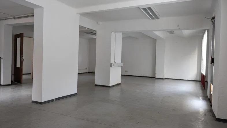 Geräumiger, heller Büroraum mit mehreren Säulen und grauem Bodenbelag, bereit zur individuellen Gestaltung.