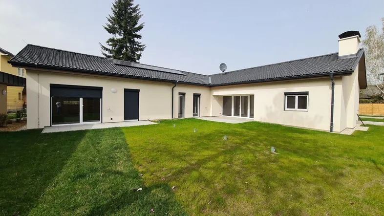 Moderne Neubau-Immobilie mit gepflegtem Rasen und Photovoltaikanlage auf dem Dach.