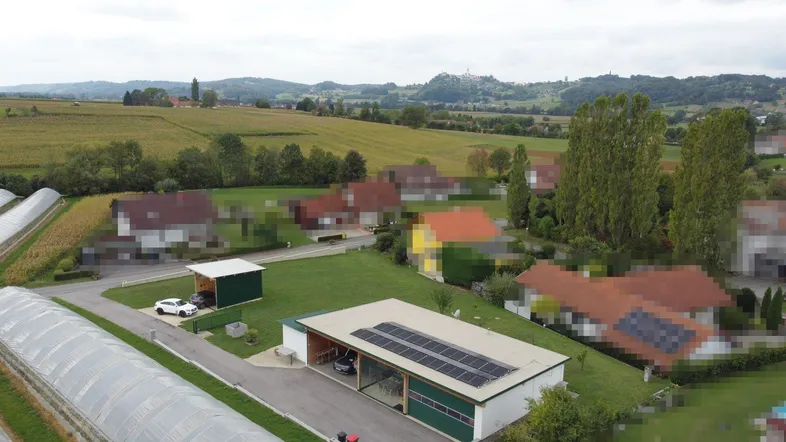 Luftaufnahme des Anwesens mit umliegenden Feldern, Wohnhäusern und einem Gebäude mit Solaranlage.