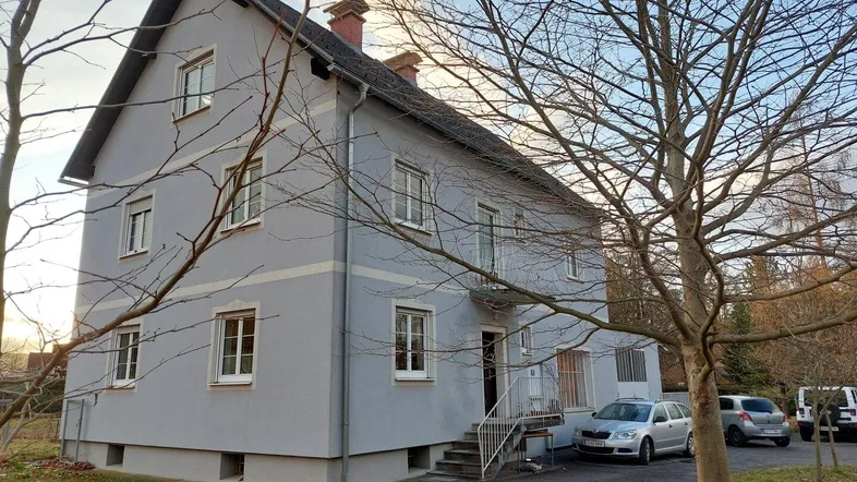Klassisches Wohnhaus mit hellblauer Fassade, Satteldach und Vorgartenbereich.