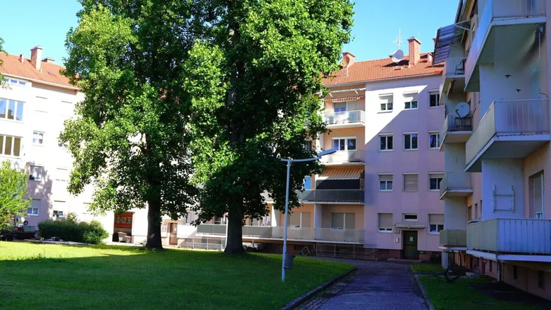 Außenansicht eines Wohngebäudes mit gepflegtem grünen Innenhof und Bäumen.
