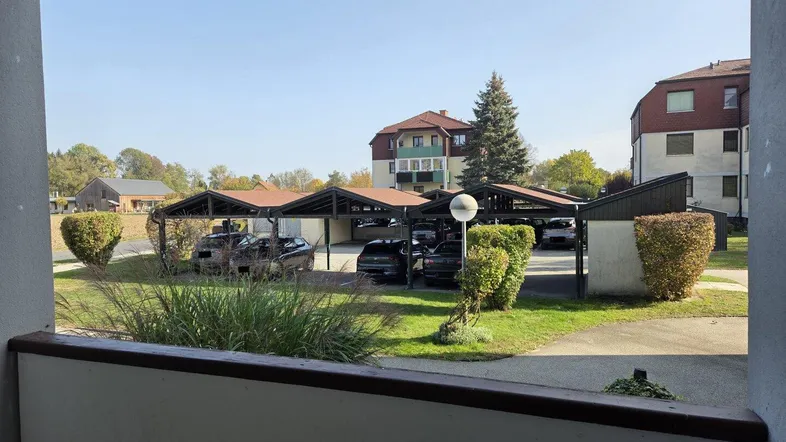 Blick vom Balkon auf die Parkplätze mit Carports und die umliegenden Wohngebäude.